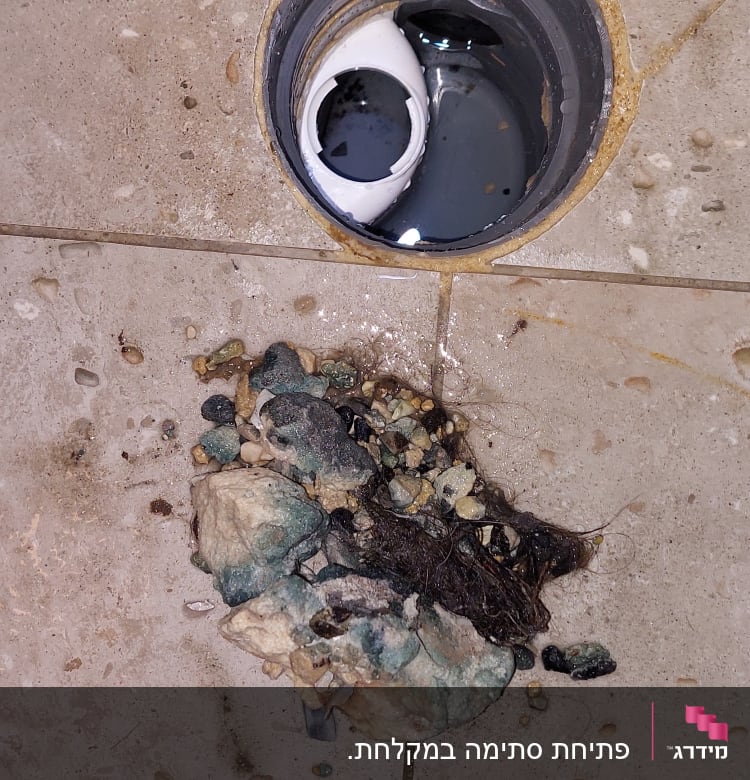 פתח ניקוז עם סתימה של אבנים ושיער